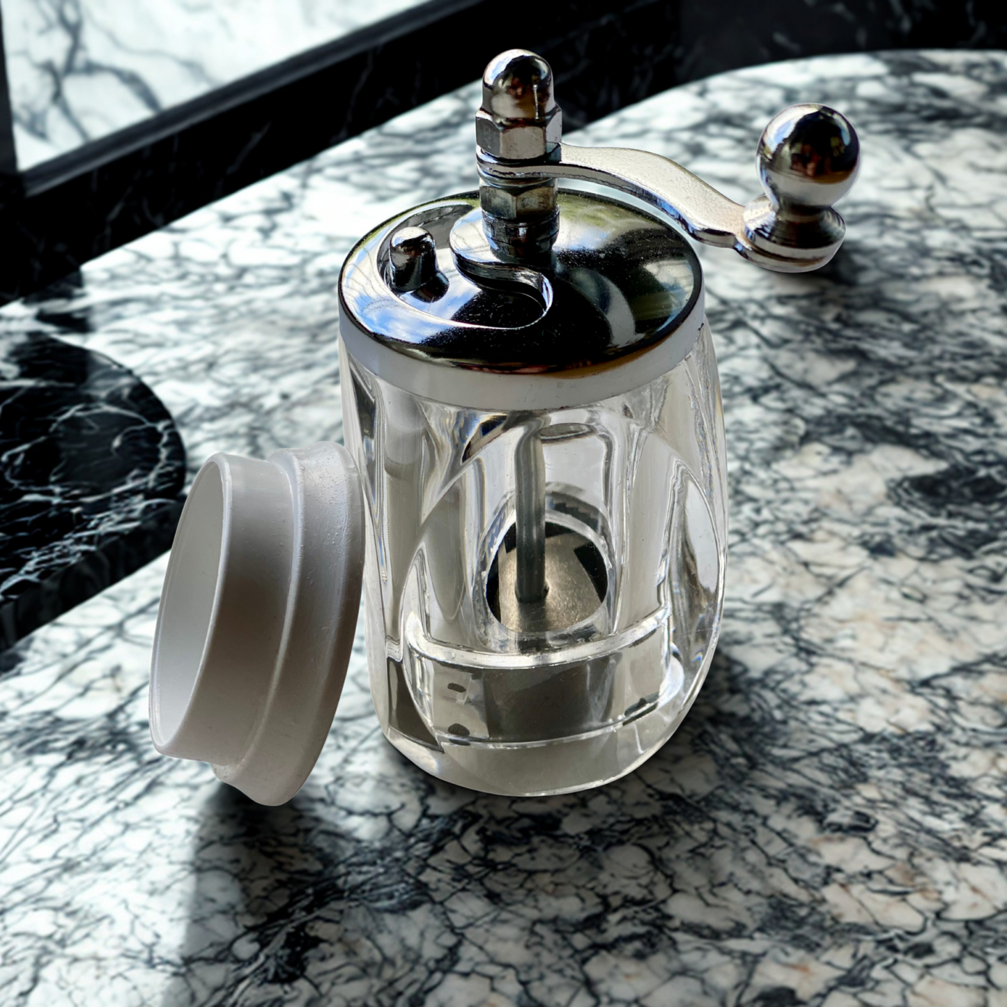 Elegante Safranmühle mit Metallkurbel auf einem Marmortisch, Deckel geöffnet.