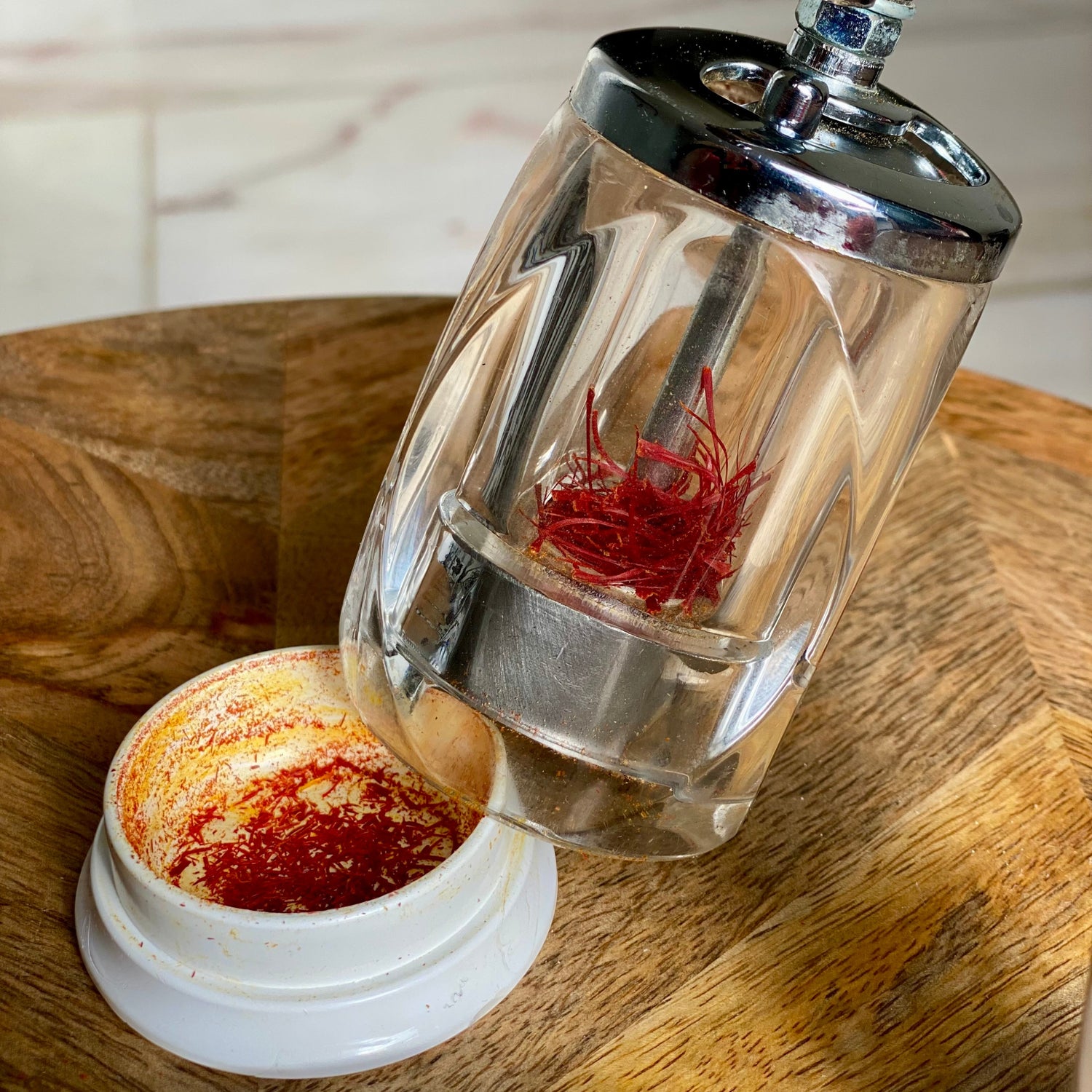 Geöffnete Safranmühle mit frisch gemahlenem Safranpulver im Deckel und Safranfäden im Mahlwerk.