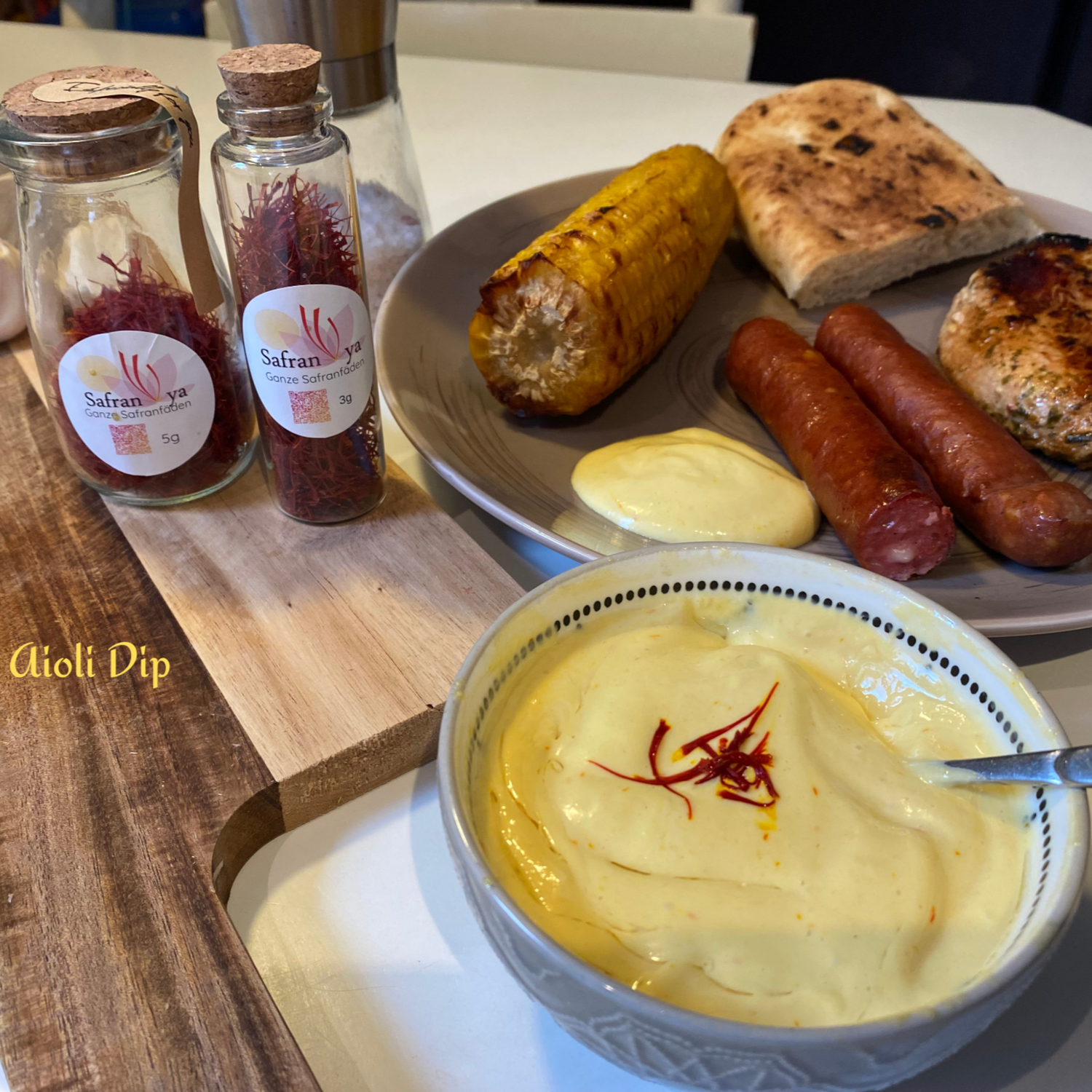 Hausgemachter Safran-Aioli Dip mit gegrilltem Fleisch, Mais und Brot, verfeinert mit Safranya Safranfäden